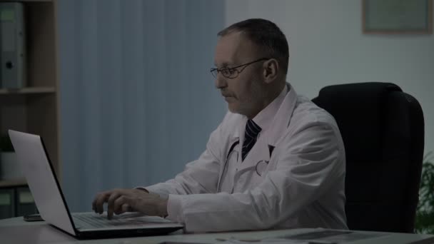 Médico de guardia nocturno llena tarjetas de los pacientes y decide tomar una siesta en silla acogedora — Vídeo de stock