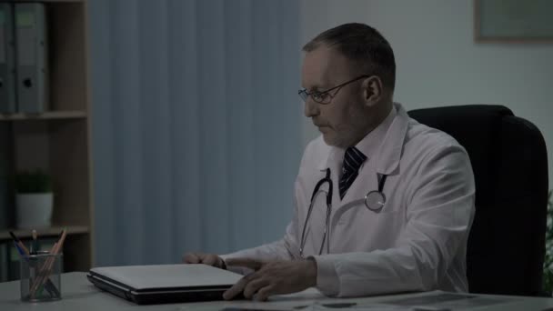 Старший опытный врач вымотан после дневной смены в больнице, перегружен работой — стоковое видео