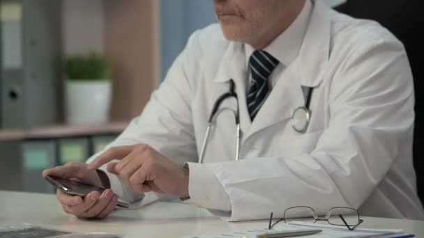 Врач с использованием нового медицинского приложения на гаджете, поиск необходимой информации — стоковое видео