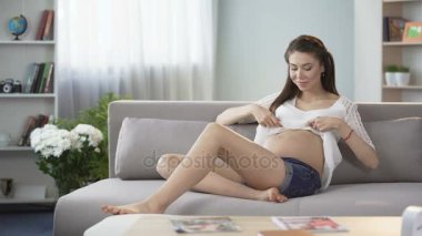 Bekliyor anne kanepe, oturma göbek, gebelik dokunmak bluz kadar koyarak