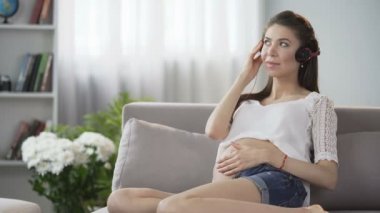 Mide hafifçe dokunarak kulaklıklar, müzik genç bekliyor kadın