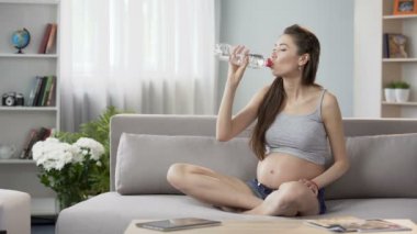 Kanepe üzerinde su dengesi, sağlık koruma İçmesuyu oturan bekliyor kadın