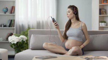 Divan, dinlerken çocukla hamile bayan rahatlatıcı müzik üstünde hareket eden telefon