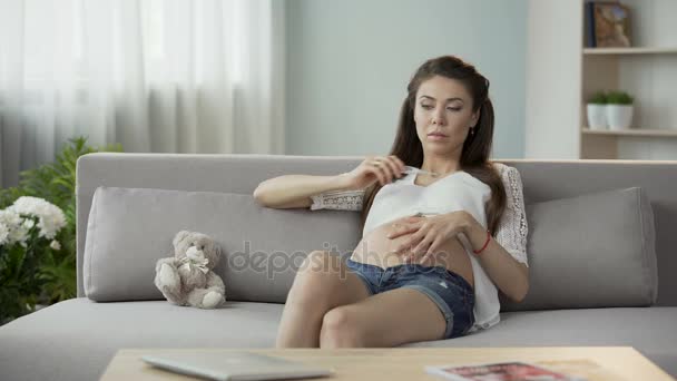 Junge schwangere Frau überprüft Körpertemperatur, schaut auf Thermometer, traurig — Stockvideo