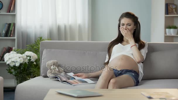 Schwangere liest Magazin, hat leichtes Übelkeitsgefühl, atmet zur Entspannung — Stockvideo