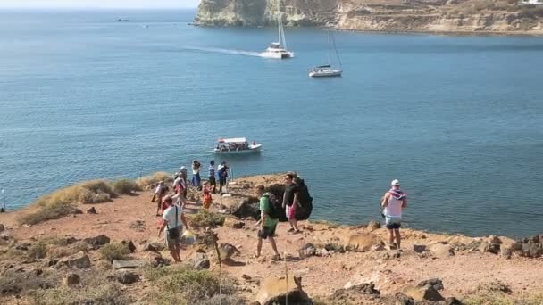 SANTORINI, GRECIA - CIRCA JULIO 2014: Turismo en la isla. Turistas descendiendo pendiente al mar, disparando espectacular vista de la isla de Santorini — Vídeos de Stock