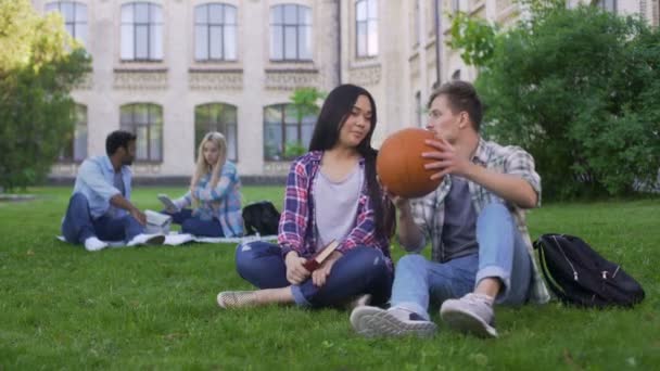Estudante masculino conversando e flertando com bela menina asiática no campus universitário — Vídeo de Stock