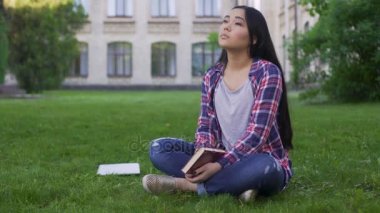 Düşünceli Asya kız öğrenci çim yalnız ve eksik ebeveynler oturan