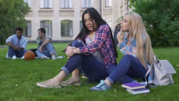 Mejores amigas sentadas en la hierba y discutiendo problemas adolescentes, apoyo — Vídeo de stock