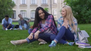 Gülümseyen ve erkekli seyir college, yakınındaki Çimenlikte oturan genç güzel kadın