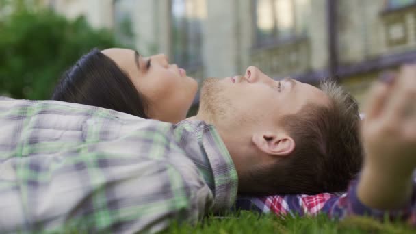 Close-up van gemengd ras paar liggen op gras en genieten van datum, tederheid, liefde — Stockvideo