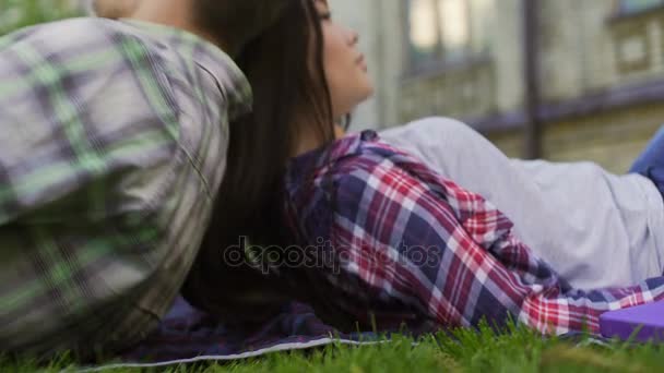 Loving couple of mixed-race teens lying on lawn, enjoying date. First love — Stock Video