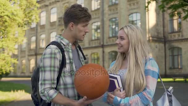 Young man talking with beautiful blonde near college, trying to impress girl — Stock Video