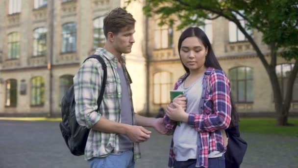 Student som försöker prata med hans asiatiska flickvän nära college, gräl, uppbrott — Stockvideo