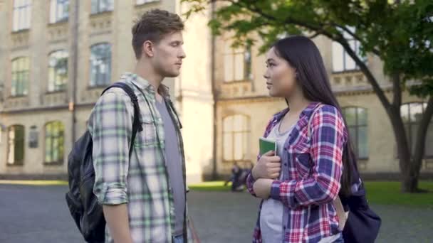 Емоційний студент-чоловік розмовляє з колишньою дівчиною біля університету, відносини — стокове відео