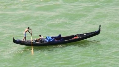 Venice, İtalya - Haziran 2016 yaklaşık: Gezi şehrin. Gondola binen erkek turist, yavaş hareket veren üstsüz Venedik kayıkçı