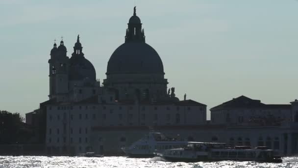 View from across channel of big cathedral located at waterside, boats moving by — Stock Video