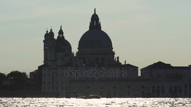 Silhouette of cathedral across glittering ruffled river, boat going down canal — Stock Video