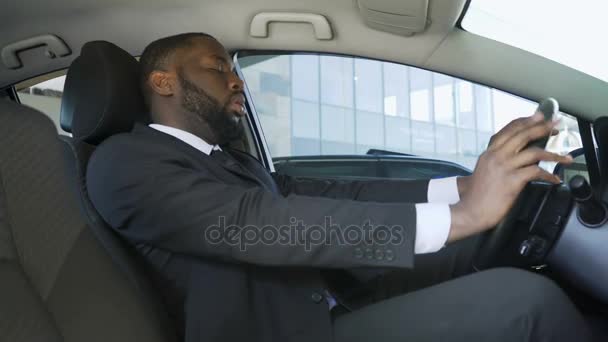 Hombre afroamericano de traje sentado en coche y bostezando, conductor de hombre de negocios — Vídeo de stock