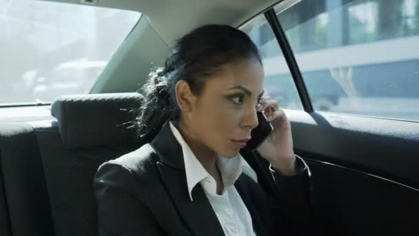 Бізнес-леді на задньому сидінні автомобіля, розмовляє по телефону, пліткує з другом — стокове відео