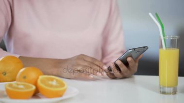 Smartphone mutfakta masada, sağlık portakal kullanan çok ırklı kız