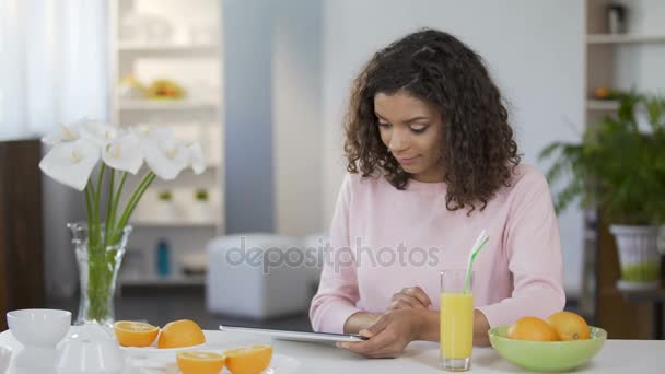 Jonge vrouw gemengd ras lezen artikel over tablet, lichaamsverzorging en voeding — Stockvideo