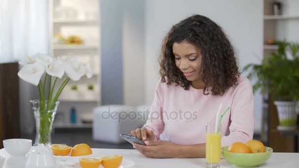 Multiracial girl typing message on mobile phone, healthy lunch break, juicing — Stock Video