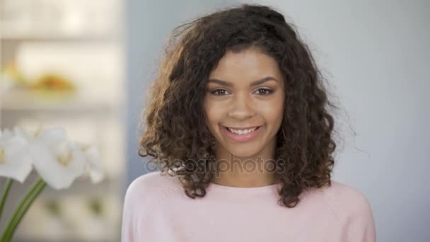 Chica de raza mixta sonriendo a la cámara, sosteniendo mitades de naranjas ante los ojos, salud — Vídeos de Stock