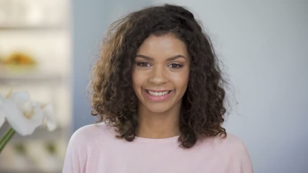 Sonriente chica multiétnica cerrando los ojos con una mitad naranja y mostrando los pulgares hacia arriba — Vídeos de Stock