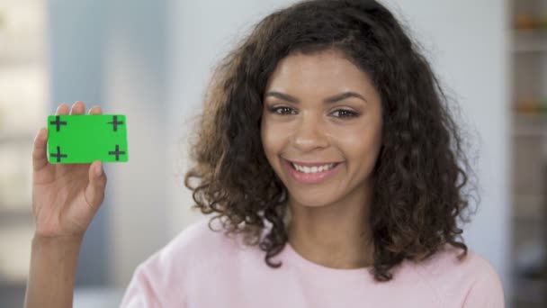 Kobieta mieszanej rasy, trzymając kartę w kolorze zielonym, uśmiechając się, opieki zdrowotnej, ogłoszenie — Wideo stockowe
