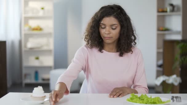 Jovem mulher bonita escolhendo salada sobre bolo e comer, comida saudável — Vídeo de Stock