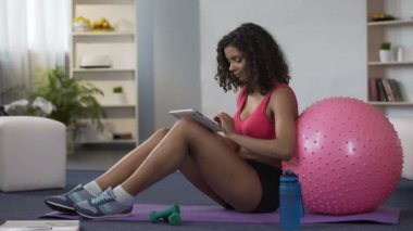 Karışık yarış spor kıyafeti tablet, online iş ile katta oturan genç bayan
