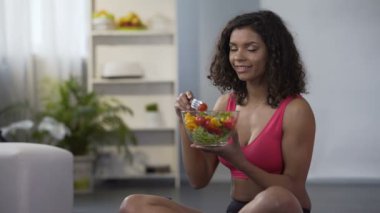 Genç kadın spor kıyafeti, katta oturan sebze salata yemek uygun diyet