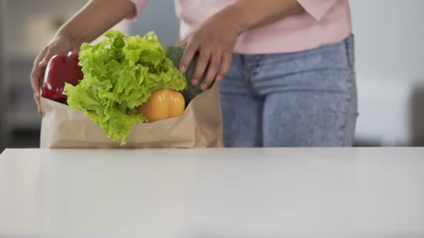 Леди берет овощи из продуктовой сумки, положить на стол, здоровое питание, диета — стоковое видео