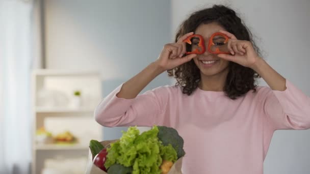 Vakker kvinne som bringer pepperringer til øynene, smilende, sunne spisevaner – stockvideo