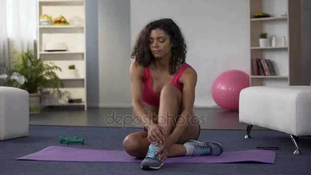 Jonge vrouw zittend op de vloer in de sportzaal outfit, op haar nek spieren uit te rekken — Stockvideo