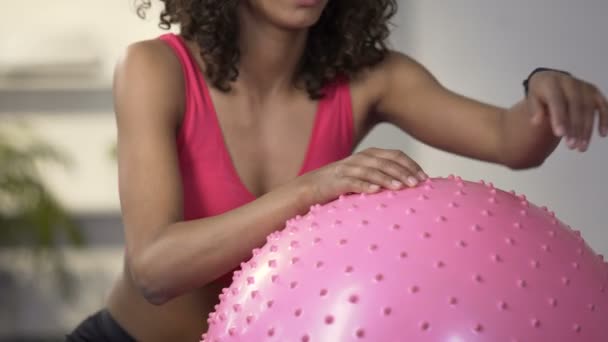 Junge zweirassige Frau lehnt sich nach gutem Training an Fitnessball und lächelt — Stockvideo