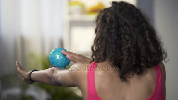 Sportieve jonge vrouw masseren wapens met het masseren van de bal, ontspannen van de lichaamsspieren — Stockvideo