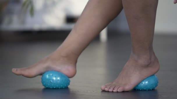 Женщина катит массажирующий шар вперед и назад ногой, болями в ногах — стоковое видео