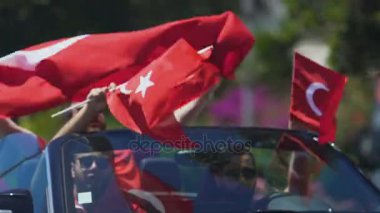 Grup Türk sakinlerinin arabanın içinde otururken ülkelerinin bayrakları sallayarak