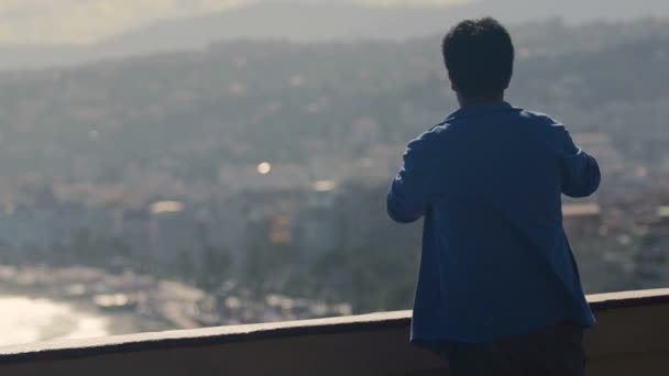 Homem rico em pé na varanda do quarto de hotel de luxo e fazendo fotos da vista da cidade — Vídeo de Stock