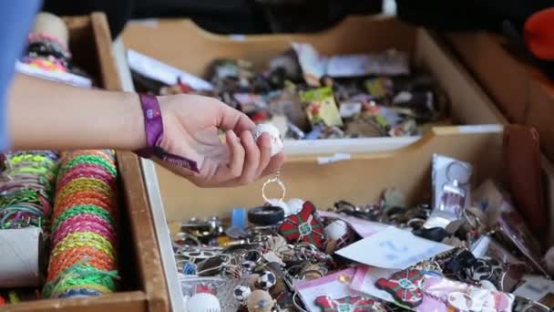 Male tourist choosing key ring souvenir from wooden box at local street market — Stock Video