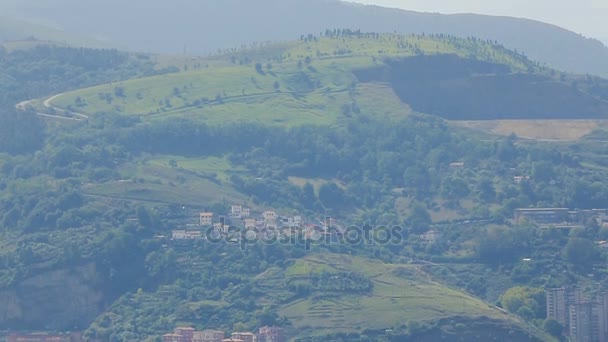 Old green mountains with big dense city at bottom, modern life and nature, pan — Stock Video