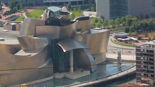 Edifício pintado dourado do Museu Guggenheim em Bilbau, pessoas caminhando na praça — Vídeo de Stock