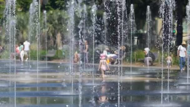 Мила дівчинка, граючи в бризок води fountain, щасливі спогади дитинства — стокове відео