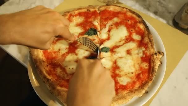 Мужчина тщательно режет традиционную неаполитанскую пиццу в уютной пиццерии — стоковое видео