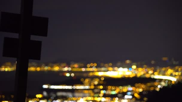 Cross silhouet tegen het luxe leven in grote verlichte stad, luchtfoto nacht weergave — Stockvideo