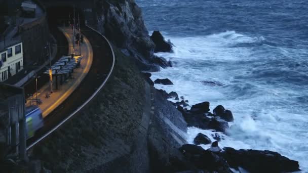 Train moving on Manarola station, slow-motion of waves breaking on rocky cliff — Stock Video