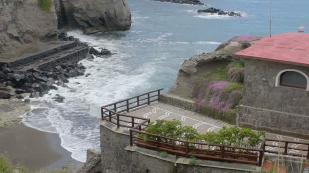 Cubierta de observación y pequeña cabaña a un lado frente a la orilla del mar con olas rodando en la orilla — Vídeos de Stock