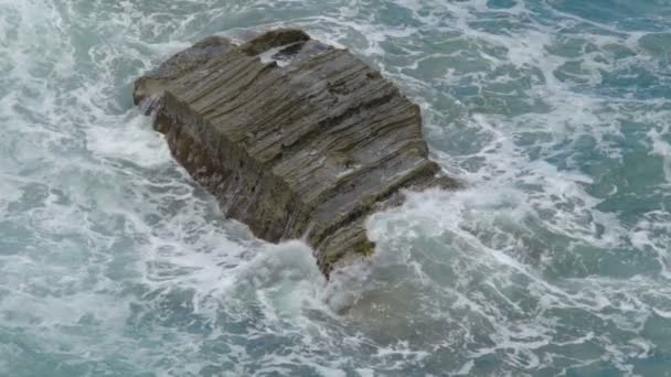 Roccia solitaria bagnata dal mare onde schiumose che irrompono in spruzzi, potenza della natura — Video Stock